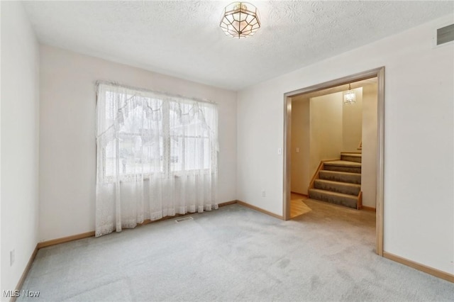 unfurnished room with a textured ceiling and light carpet