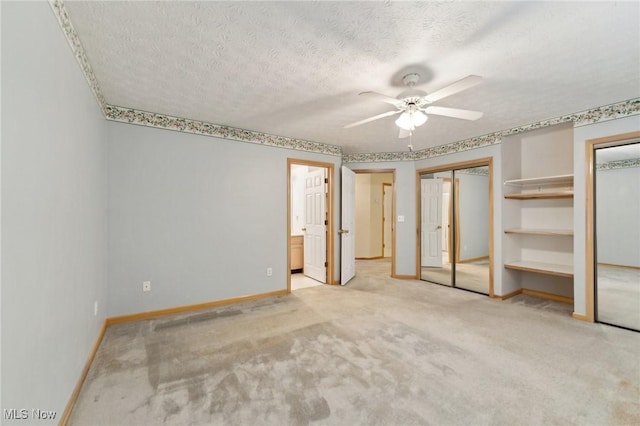 unfurnished bedroom featuring ensuite bath, ceiling fan, light carpet, and a textured ceiling