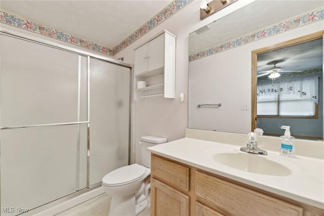 bathroom featuring vanity, toilet, a shower with door, and ceiling fan