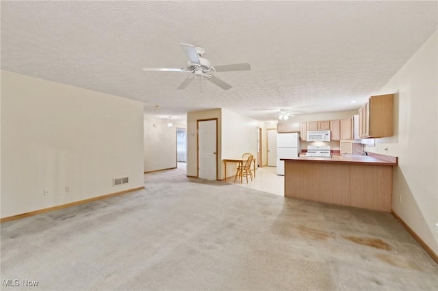 unfurnished living room featuring ceiling fan, light colored carpet, and a textured ceiling