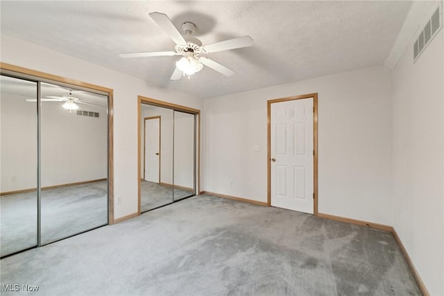 unfurnished bedroom featuring ceiling fan, carpet floors, and two closets