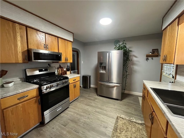 kitchen featuring appliances with stainless steel finishes, light hardwood / wood-style flooring, and sink