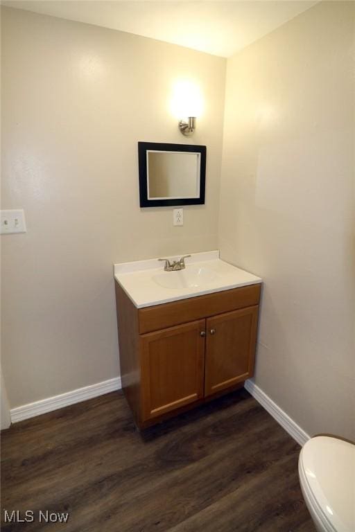 bathroom featuring vanity, wood-type flooring, and toilet