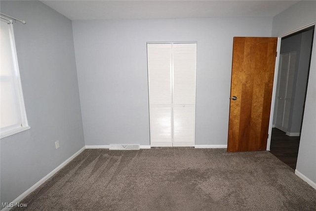 unfurnished bedroom featuring dark colored carpet and a closet