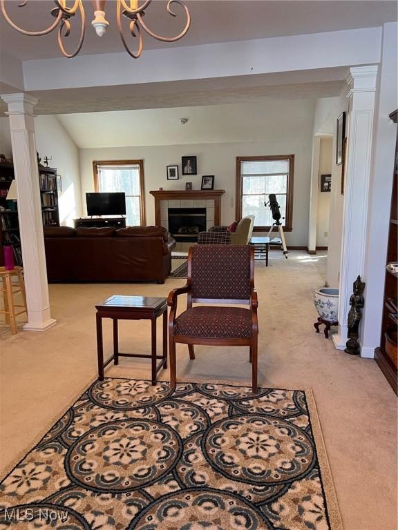 carpeted living room featuring decorative columns, plenty of natural light, a notable chandelier, and a fireplace