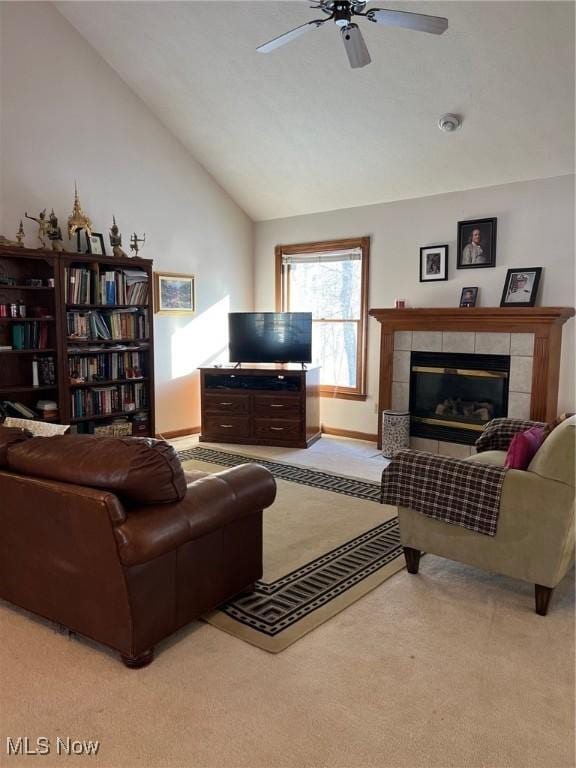 living room featuring vaulted ceiling, ceiling fan, light carpet, and a tiled fireplace