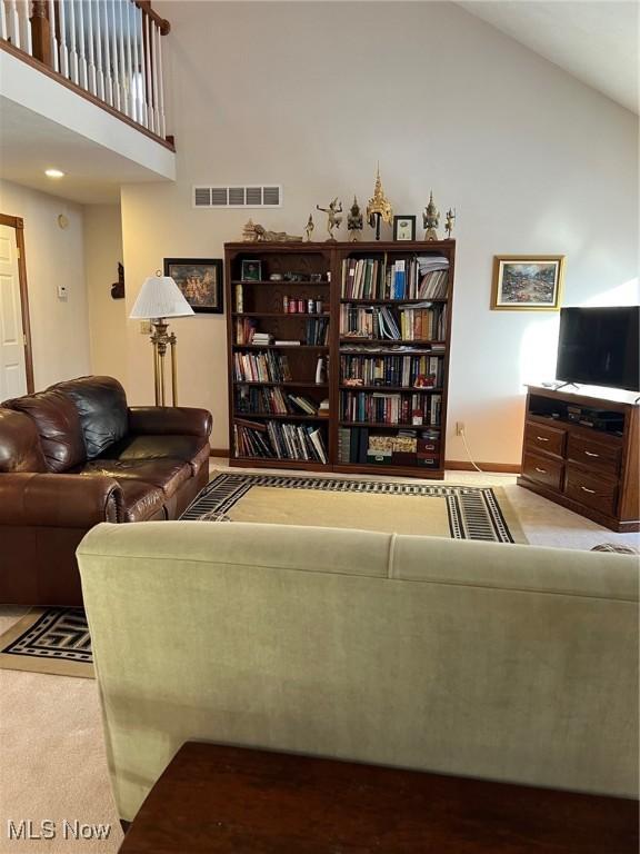 carpeted living room with high vaulted ceiling