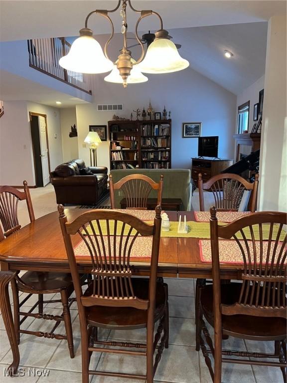 dining room featuring tile patterned floors, lofted ceiling, and a chandelier