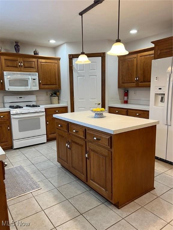 kitchen with a kitchen island, white appliances, pendant lighting, and light tile patterned floors