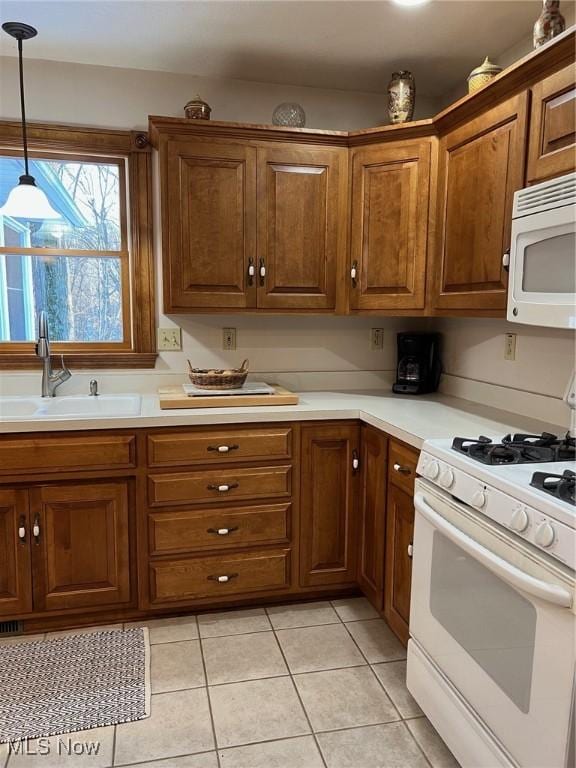 kitchen with pendant lighting, sink, white appliances, and light tile patterned flooring