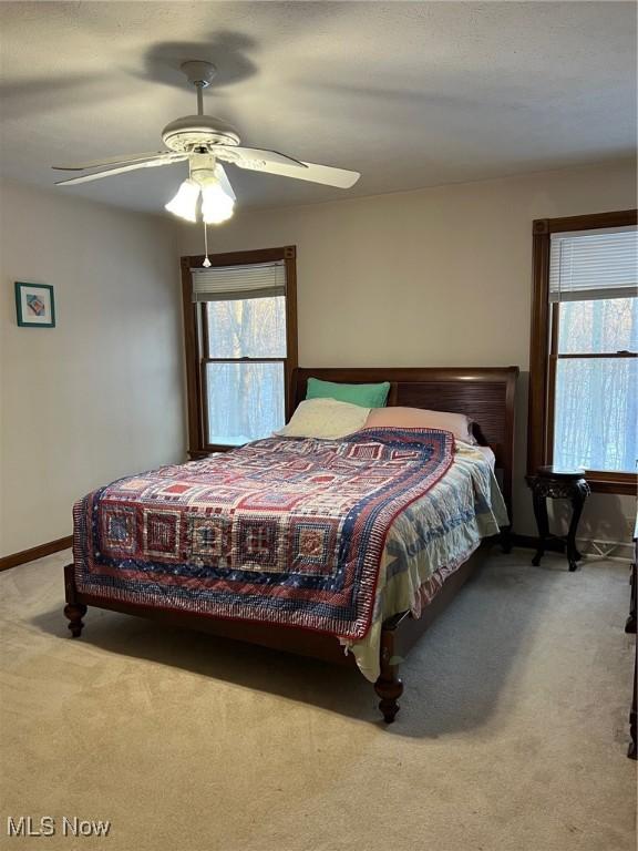 carpeted bedroom featuring multiple windows and ceiling fan