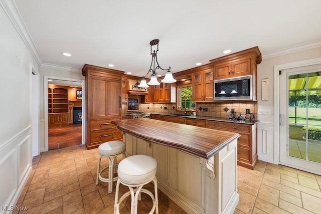 kitchen with pendant lighting, a center island, sink, butcher block counters, and black microwave