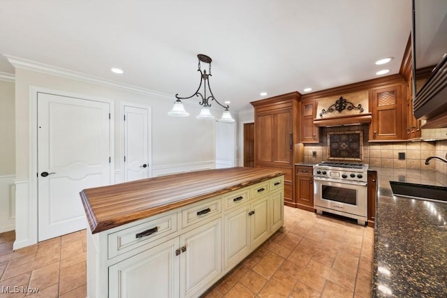 kitchen featuring high end stainless steel range oven, sink, decorative light fixtures, a center island, and butcher block countertops