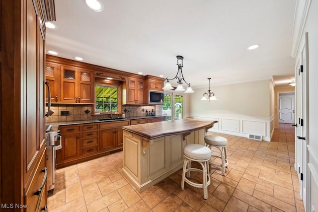 kitchen with built in microwave, a center island, sink, hanging light fixtures, and a kitchen bar