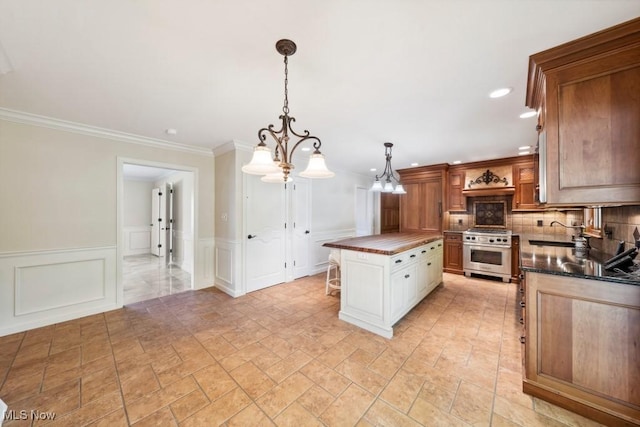 kitchen featuring a center island, white cabinets, ornamental molding, stainless steel range, and decorative light fixtures