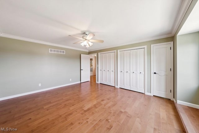 unfurnished bedroom featuring multiple closets, ceiling fan, crown molding, and light hardwood / wood-style flooring