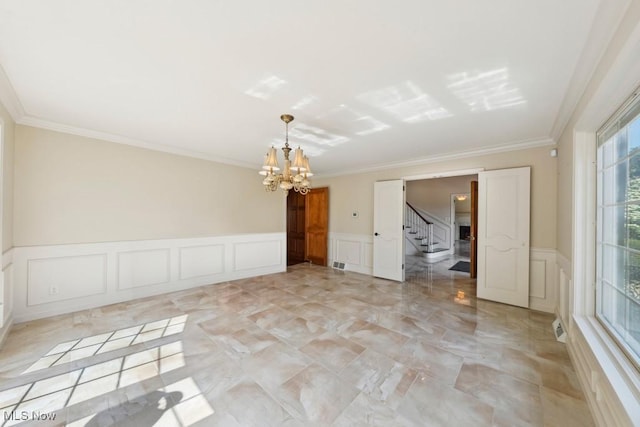 empty room featuring ornamental molding and an inviting chandelier