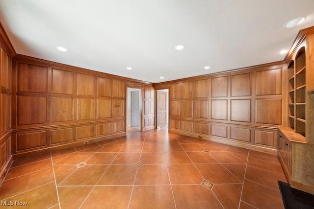 spare room featuring built in features, tile patterned floors, and wooden walls