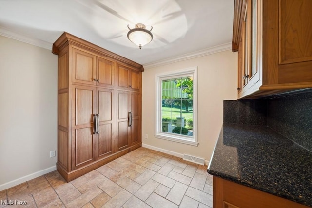 interior space featuring crown molding and dark stone countertops