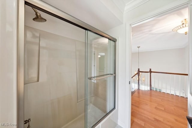 bathroom with hardwood / wood-style flooring, a shower with shower door, and crown molding