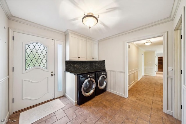 clothes washing area featuring cabinets, crown molding, and washing machine and clothes dryer