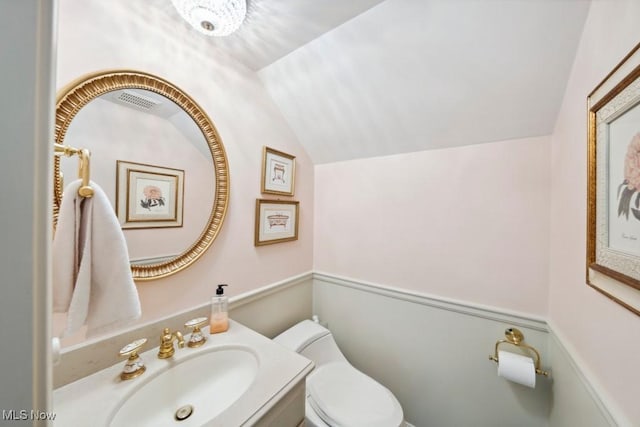 bathroom with vanity, toilet, and lofted ceiling