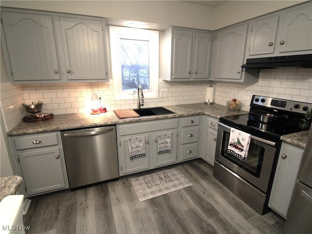 kitchen with backsplash, dark wood-type flooring, sink, and stainless steel appliances