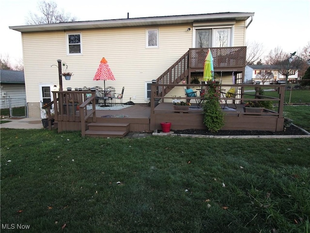 back of property with outdoor dining area, a lawn, and a wooden deck