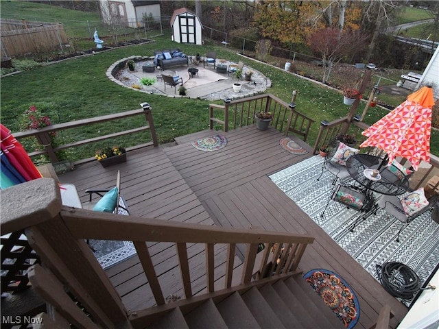 wooden deck with an outbuilding, a lawn, outdoor dining space, a shed, and a fenced backyard