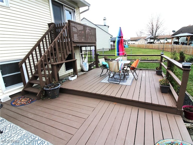 deck with fence, stairway, a lawn, and outdoor dining space