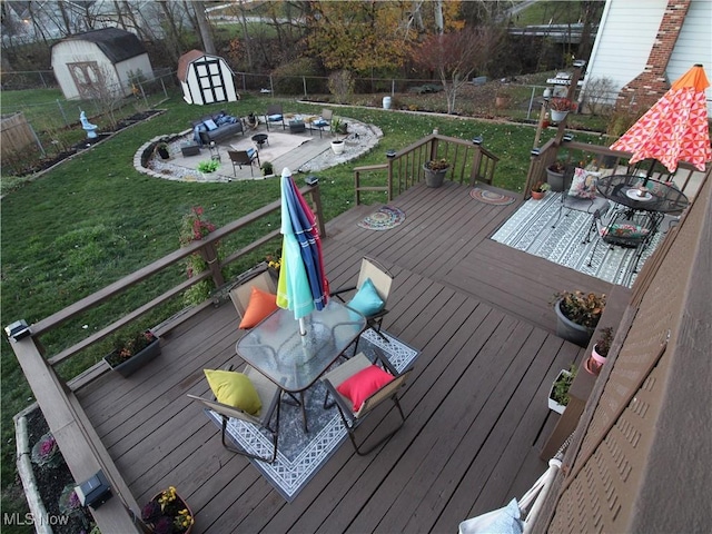 wooden terrace with a yard, a storage unit, an outdoor structure, and a fenced backyard