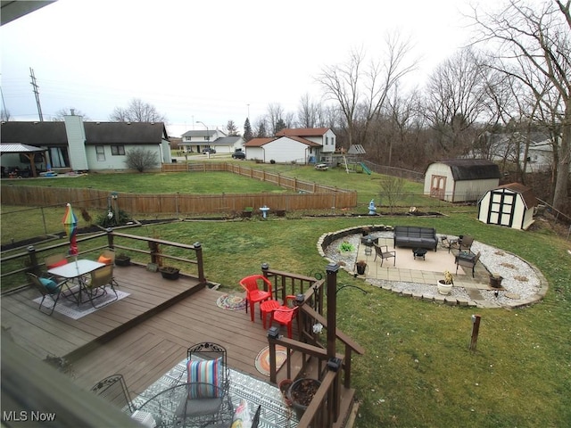 wooden terrace with an outdoor fire pit, an outbuilding, a yard, a shed, and a playground