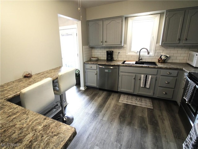 kitchen featuring dark wood finished floors, white microwave, a sink, gray cabinetry, and stainless steel dishwasher