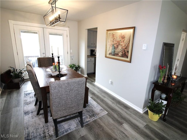 dining area featuring dark wood-type flooring, french doors, a notable chandelier, and baseboards