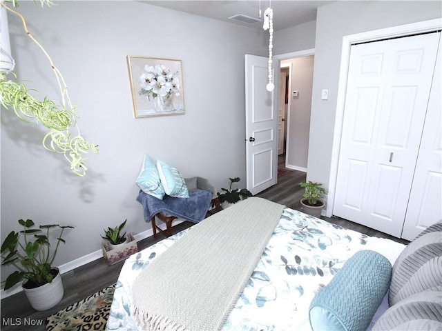 bedroom featuring visible vents, a closet, baseboards, and dark wood-style flooring