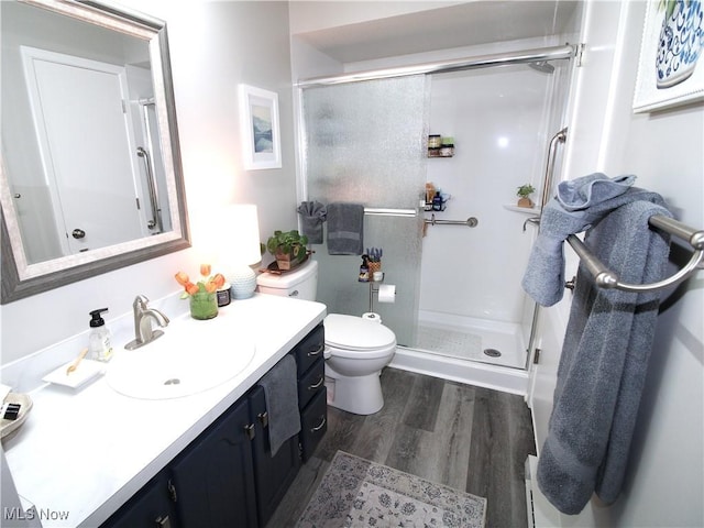 bathroom featuring toilet, wood finished floors, vanity, and a shower stall