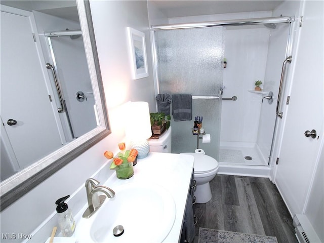 full bathroom featuring a baseboard heating unit, a stall shower, toilet, and wood finished floors