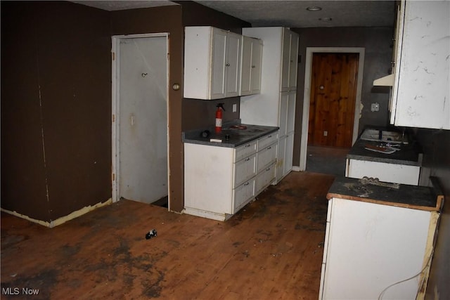 kitchen featuring white cabinets, dark wood-type flooring, and range hood