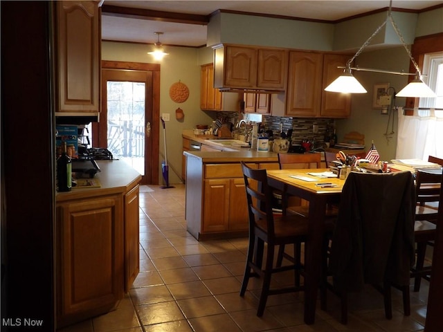 kitchen with decorative backsplash, ornamental molding, sink, pendant lighting, and light tile patterned flooring