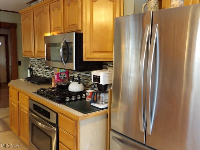 kitchen with decorative backsplash, appliances with stainless steel finishes, and light tile patterned floors