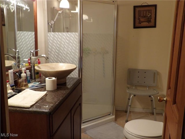 bathroom featuring tile patterned flooring, vanity, toilet, and a shower with shower door