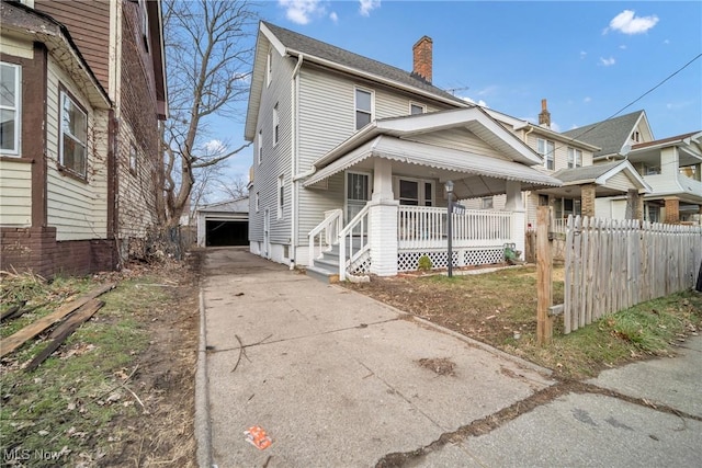 view of front of property featuring covered porch, a garage, and an outdoor structure