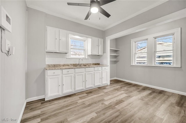 kitchen featuring white cabinetry, sink, ceiling fan, crown molding, and light wood-type flooring