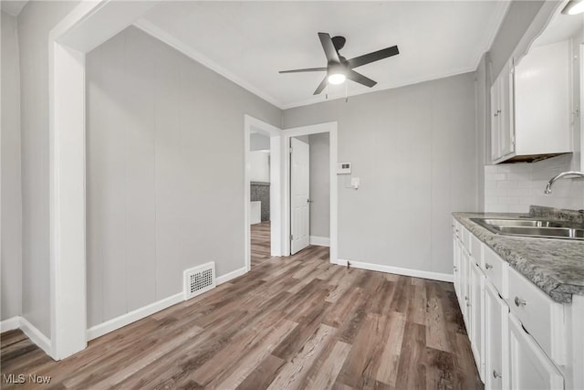 kitchen featuring ceiling fan, sink, light wood-type flooring, white cabinets, and ornamental molding