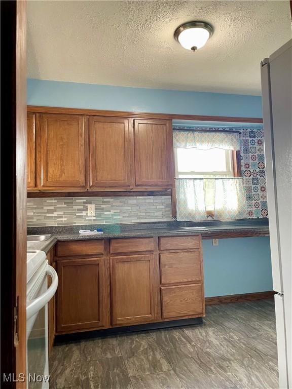 kitchen featuring backsplash, white range with electric cooktop, and a textured ceiling