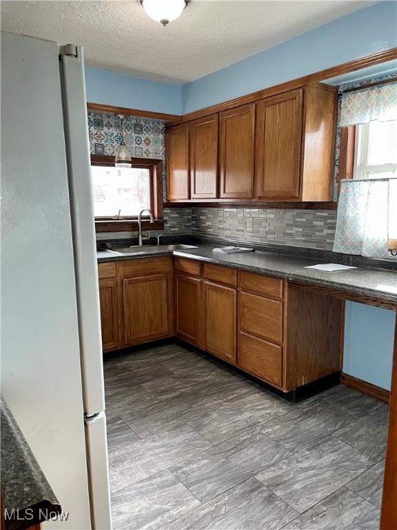 kitchen with a textured ceiling, white refrigerator, sink, and tasteful backsplash