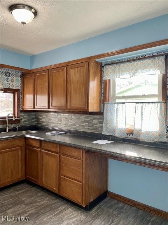 kitchen featuring backsplash, sink, a textured ceiling, and dark hardwood / wood-style floors