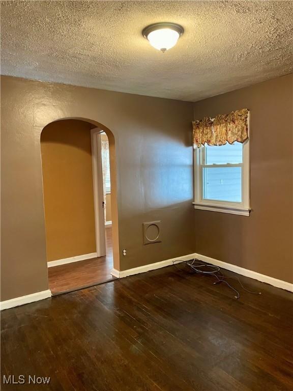 unfurnished room featuring a textured ceiling and dark wood-type flooring