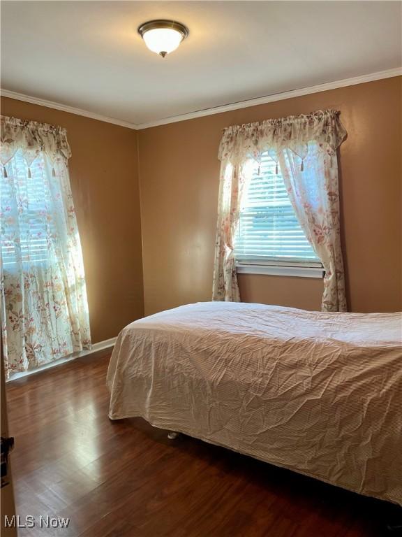 unfurnished bedroom with dark hardwood / wood-style floors and ornamental molding