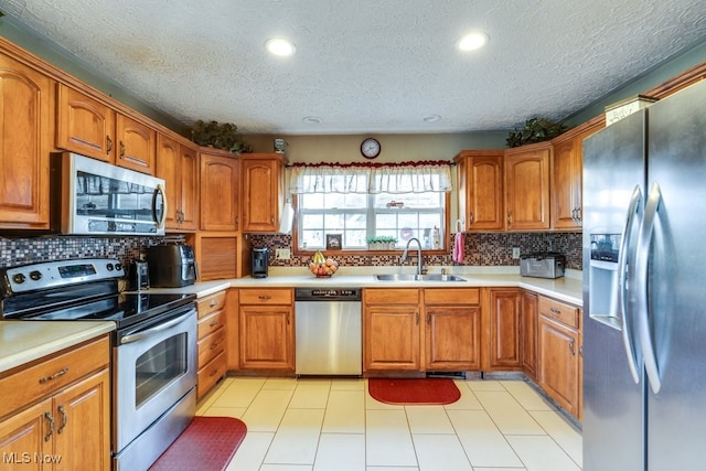 kitchen with decorative backsplash, a textured ceiling, stainless steel appliances, and sink